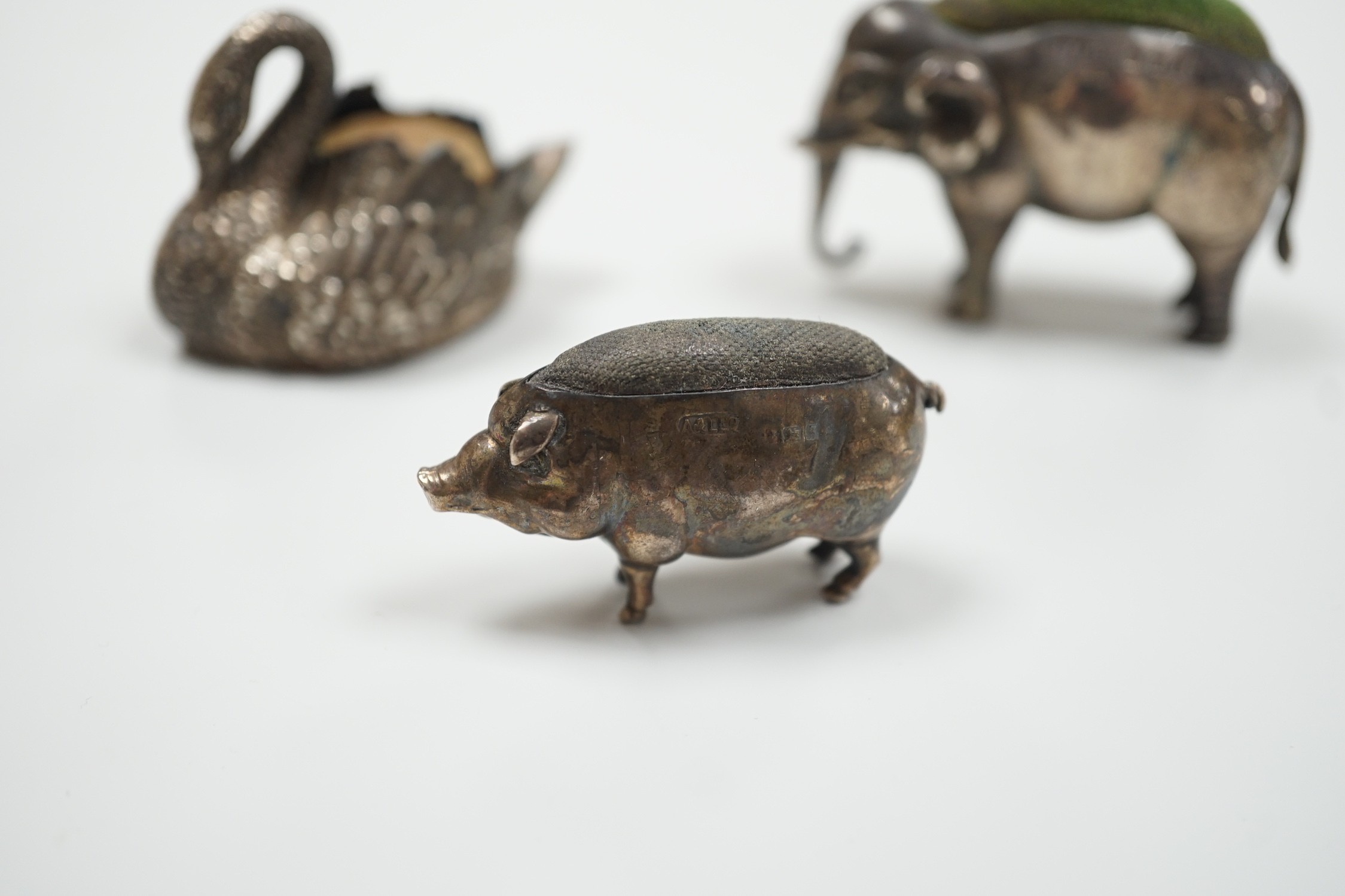 An Edwardian silver elephant pin cushion, Adie & Lovekin, Birmingham, 1905, length 62mm, a similar pig and late Victorian swan pin cushions.